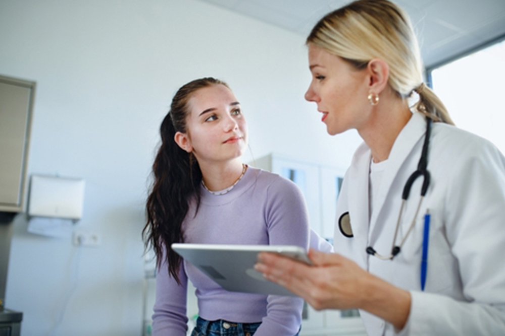 Young woman doctor explaining diagnosis to teenage girl in her ambulance.